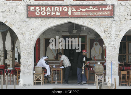 Qatar, Doha, les hommes assis devant un café chicha fumer Banque D'Images