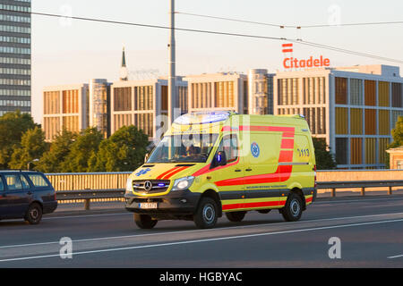 Riga, Lettonie - 30 juin 2016 : Déménagement avec sirène d'urgence Réanimation Ambulance jaune vif Van Voiture sur pont Vansu. La construction d'Citadele Bank B Banque D'Images