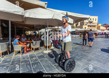 Femme âgée et touristique dans le vieux port vénitien utilisant segway, Chania, Crète, Grèce Banque D'Images