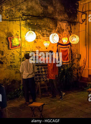 Deux hommes jouant un jeu d'échecs chinois de grande taille dans la nuit, dans les rues de Hoi An, Vietnam. Banque D'Images