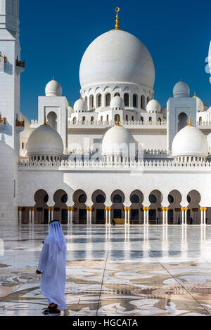 Moyen-orient traditionnellement habillé homme marchant dans la cour intérieure de la mosquée Sheikh Zayed, Abu Dhabi, Émirats Arabes Unis Banque D'Images