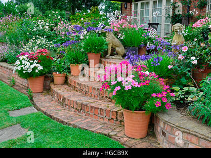 Terrasse jardin coloré avec des lits de fleurs et planté des conteneurs un affichage très attractice en face d'une maison de campagne Banque D'Images