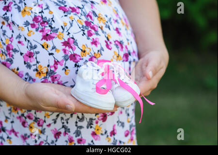 Jeune mère enceinte enfant chaussures blanc détient Banque D'Images