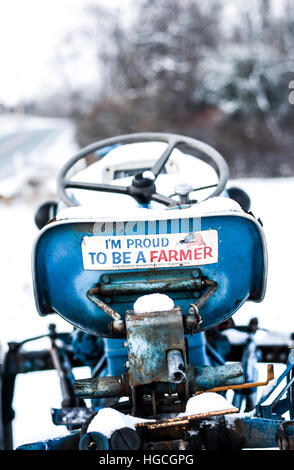 Un agriculteur fierté autocollant sur un tracteur Ford bleu vintage dans la neige Banque D'Images