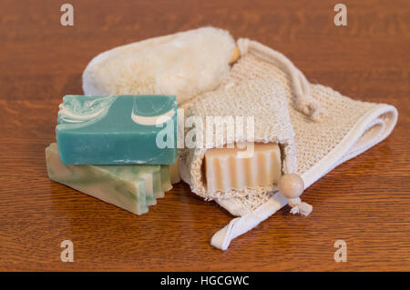 Close up de trois barres de savon lait de chèvre, un en ramie sur porte-savon avec gant de lavage du corps à l'arrière sur la table en bois. Banque D'Images