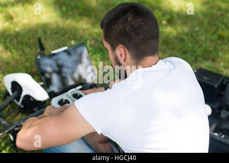 Jeune ingénieur avec contrôle à distance La préparation au vol d'un drone in Park Banque D'Images