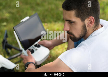 Jeune ingénieur avec contrôle à distance La préparation au vol d'un drone in Park Banque D'Images