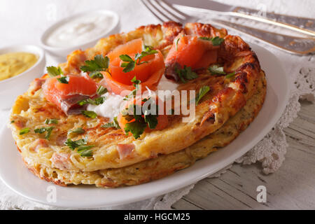 Swiss galettes de pommes de terre avec le saumon fumé et la sauce sur une plaque horizontale de près. Banque D'Images