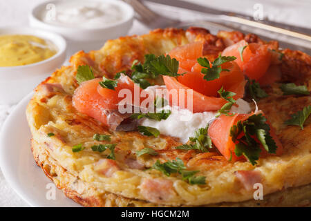 Galettes de pommes de terre avec le saumon fumé et la sauce sur une plaque horizontale de près. Banque D'Images