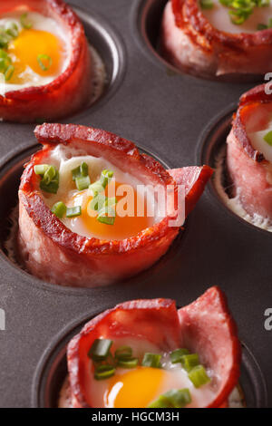 Des petits œufs enveloppés dans du bacon close up dans le plat de cuisson verticale. Banque D'Images