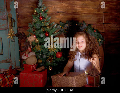 Happy little girl décoration arbre de Noël dans la belle salle de séjour avec cheminée traditionnelle. Banque D'Images