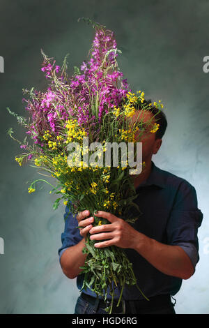 Homme tenant un énorme bouquet de fleurs sauvages, un homme est venu sur une date avec des fleurs, l'homme en attente de son amour Banque D'Images