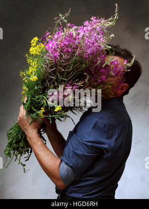 Homme tenant un énorme bouquet de fleurs sauvages, un homme est venu sur une date avec des fleurs, l'homme en attente de son amour Banque D'Images