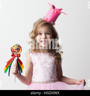 Belle petite princesse candy girl in crown holding big lollipop and smiling Banque D'Images