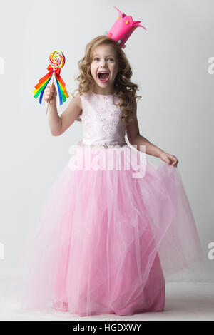 Belle petite princesse candy girl in crown holding big lollipop and smiling Banque D'Images