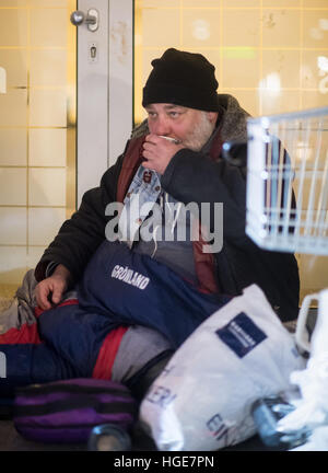 L'homme sans foyer Ben buvant un café que lui a donné une mission dans la ville bus à son endroit pour dormir dans un grand magasin durant des températures de moins-neuf degrés à Munich, Allemagne, 06 janvier 2017. Les supporteurs bénévoles du 'Kaeltebusses'(lt. Les autobus à froid) en voiture à la réunion et de places de couchage des personnes sans-abri la nuit pour leur donner les aliments chauds et les boissons à apporter un certain soulagement sur les nuits froides. Photo : Matthias Balk/dpa Banque D'Images