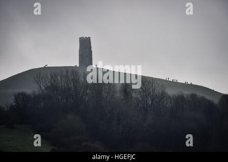 Les gens grimper vers St Michael's Tower au sommet de Glastonbury Tor, dans misty et brumeux sur Somerset Levels. Banque D'Images
