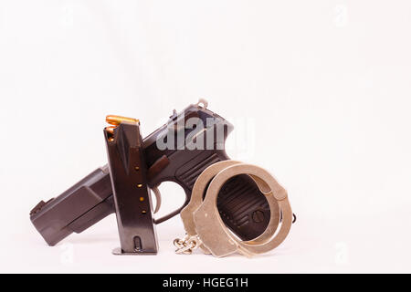 Clip, pistolet et menottes avec un fond blanc. Banque D'Images