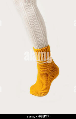 Les jambes des femmes en blanc bas et chaussettes tricotées jaune. Banque D'Images