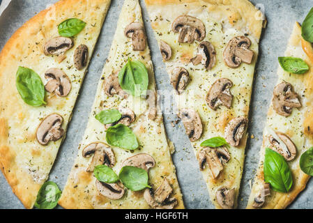 Des pizzas au basilic coupé en tranches sur du papier sulfurisé Banque D'Images