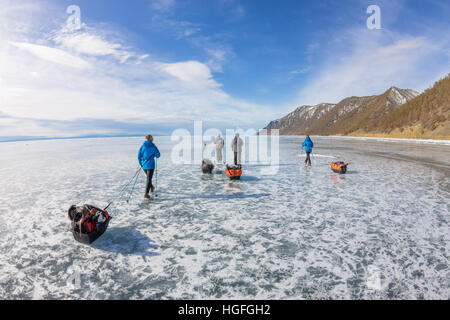 Femme et un homme avec un traîneau et pôle trekking a de la glace du lac Baïkal Banque D'Images