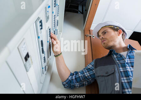 Les jeunes electrician working on panneau électrique Banque D'Images