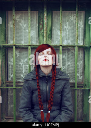 Jeune femme rousse, avec deux longues tresses, assis près d'une vieille fenêtre Banque D'Images