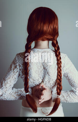 Jeune femme rousse avec deux longues tresses retour à l'appareil photo Banque D'Images