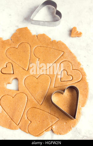 Faire des cookies en forme de cœur de gingembre pâte crue - des biscuits de fête pâtisserie pour la Saint-Valentin Banque D'Images