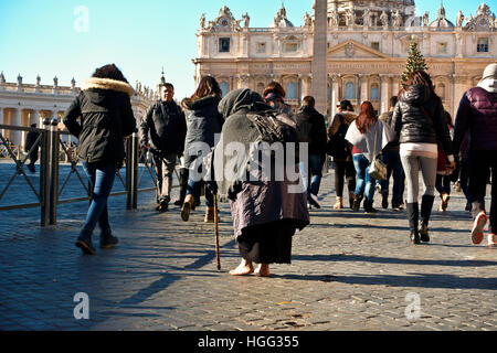 Mendiant non identifié mendiant parmi une foule de gens passant par la place Saint-Pierre. Vatican, Rome, Italie, Europe, Union européenne, UE. Banque D'Images