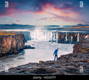 Debout sur le tourisme debout sur le bord d'une rivière Jokulsa Fjollum à main levée et d'apprécier le lever du soleil. Scène d'été colorés sur la Selfoss Wa Banque D'Images