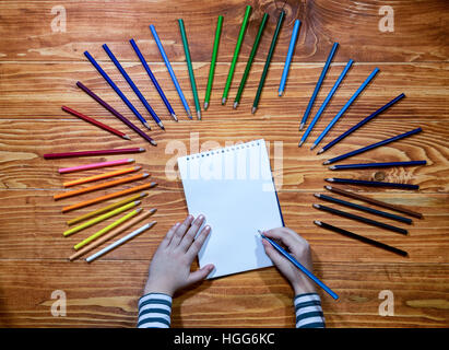 Les mains de l'enfant écrit sur un ordinateur portable avec des crayons de couleur vide autour de la table en bois Banque D'Images