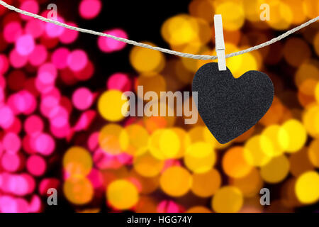 Coeur noir pendu sur la corde de chanvre sur abstract colorful bokeh background et ont à gérer l'espace de copie le texte que vous voulez. Banque D'Images