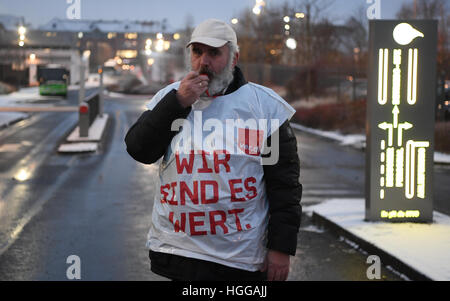 Fulda, Allemagne. Jan 9, 2017. Un chauffeur de bus en grève avec un gilet à lire 'Nous sommes en valeur elle' se trouve dans l'allée de la gare d'autobus de l'RhoenEnergie à Fulda, Allemagne, le 9 janvier 2017. Le syndicat Verdi a appelé à une grève illimitée de l'ensemble, les conducteurs de bus. Verdi est en train de négocier une nouvelle convention collective accord salarial avec l'état de Hesse association entreprises Omnibus. Photo : Arne Dedert/dpa/Alamy Live News Banque D'Images