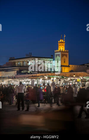 Foule, distributeur des stalles et minaret au crépuscule, la place Jemaa El Fna, Marrakech, Maroc Banque D'Images