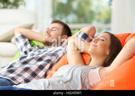 Couple ou colocation sur relaxant poufs confortable dans la salle de séjour à la maison Banque D'Images