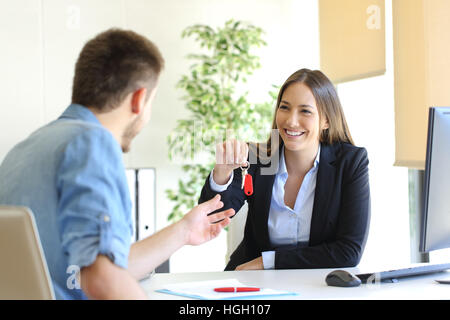 Heureux d'avoir des clés de la maison à un client après la signature de contrat dans le bureau Banque D'Images