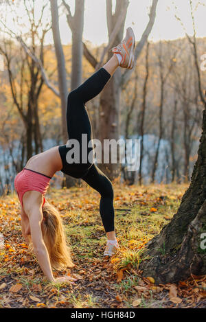 Belle femme exceptionnelle de faire des exercices d'étirement en plein air dans le parc. L'exercice de modèle sport féminin automne plein air parc. fille souple Banque D'Images