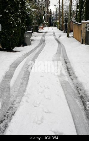 Les traces de pneu et empreintes de pas dans un couloir de neige dans une zone résidentielle, Vancouver, Canada Banque D'Images