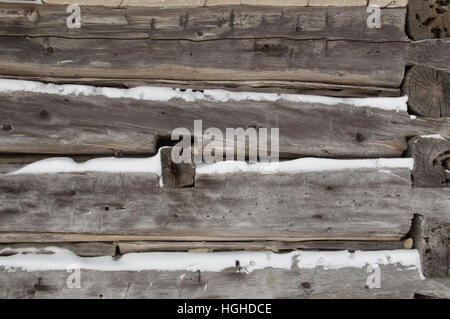 Un hiver festif avec arrière-plan gris argenté vieilli 38mm horizontal avec la neige en entre. Sciage aller vers le coin de bâtiment avec log e Banque D'Images