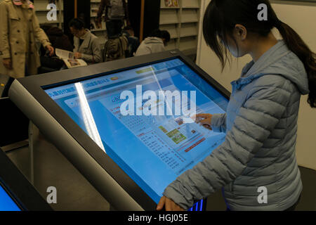 Girl reading journal électronique à une bibliothèque en Chine Banque D'Images