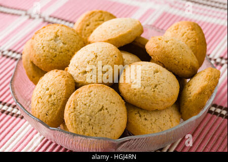 De savoureux biscuits à la cardamome brun doré petit bol en verre sur la nappe rose. Banque D'Images