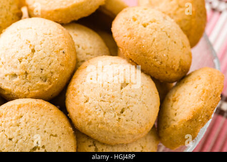 De savoureux biscuits à la cardamome brun doré petit bol en verre sur la nappe rose. Banque D'Images