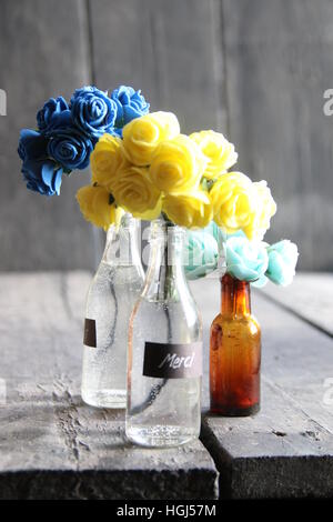 Merci tag et fleurs de nice dans les bouteilles sur la table en bois Banque D'Images