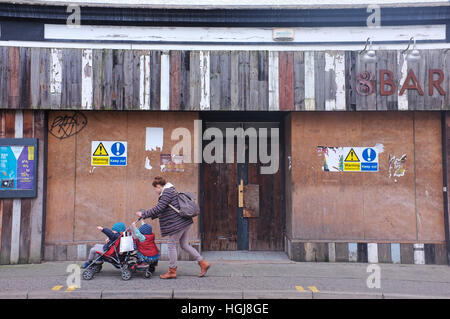 Une femme marche passé une entreprise fermée à Falmouth, Cornwall, UK Banque D'Images