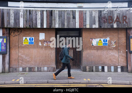 Un homme qui marche devant une entreprise fermée à Falmouth, Cornwall, UK Banque D'Images