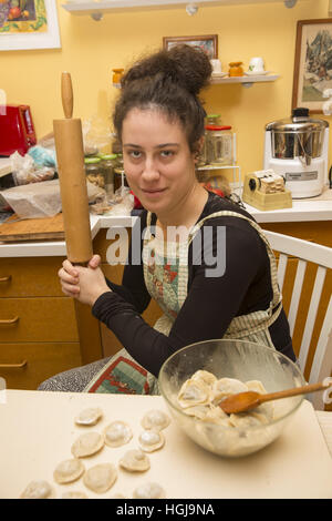 Jeune femme pose avec son rouleau à pâtisserie faire pierogi (raviolis polonais) pour un réveillon de Noël traditionnel à Brooklyn, New York. Banque D'Images