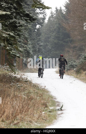 Les vététistes bravant la neige autour de la société Alwen réservoir dans le comté de Conwy, Pays de Galles, Royaume-Uni Banque D'Images