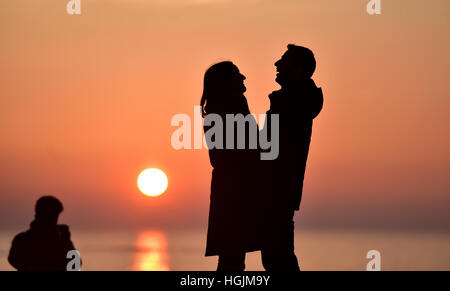 Brighton, Sussex, UK. 22 janvier, 2017. Un couple profitez d'un moment romantique sur la plage de Brighton à mesure que le soleil se couche derrière eux au crépuscule, après une froide mais belle journée sur la côte sud Crédit : Simon Dack/Alamy Live News Banque D'Images