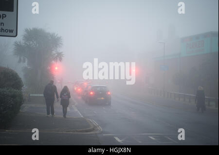 Un matin brumeux sur les voitures d'attente attendre dans une ligne de la circulation à un passage à niveau dans le West Sussex, Angleterre, Royaume-Uni. Banque D'Images